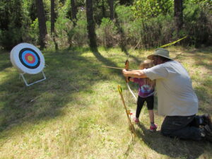 man teaching girl archery